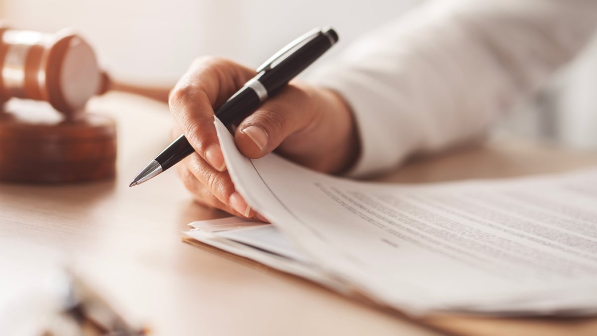 Legal documents being signed at a table with notary seal and pen
