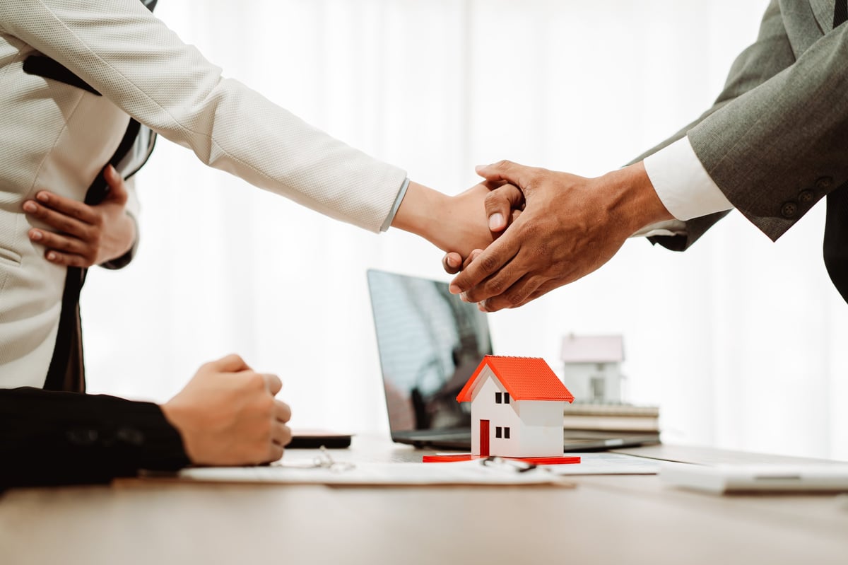 Real estate agents presenting model homes to clients with mortgage loan documents